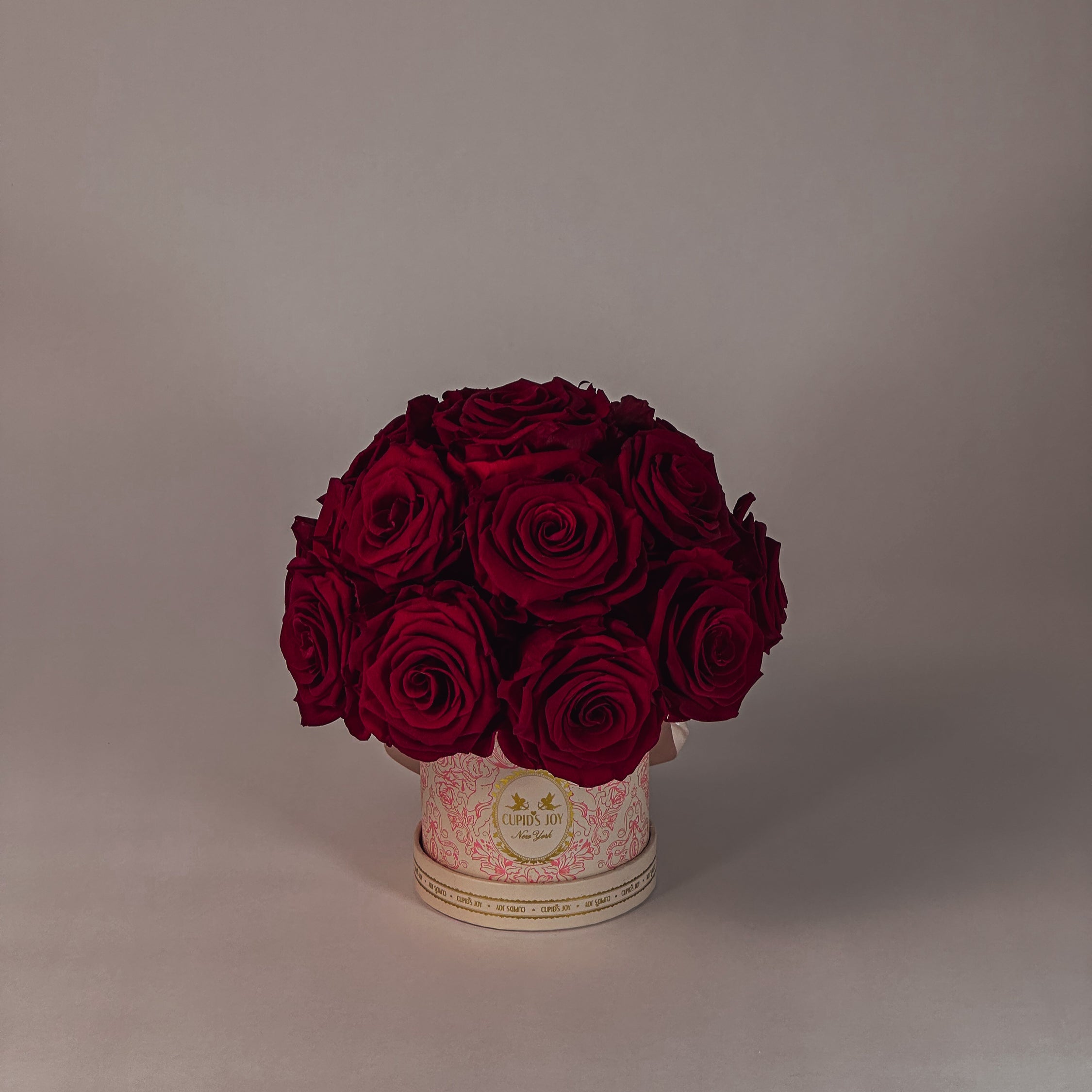 Bouquet of red forever roses in a decorative box on a plain background