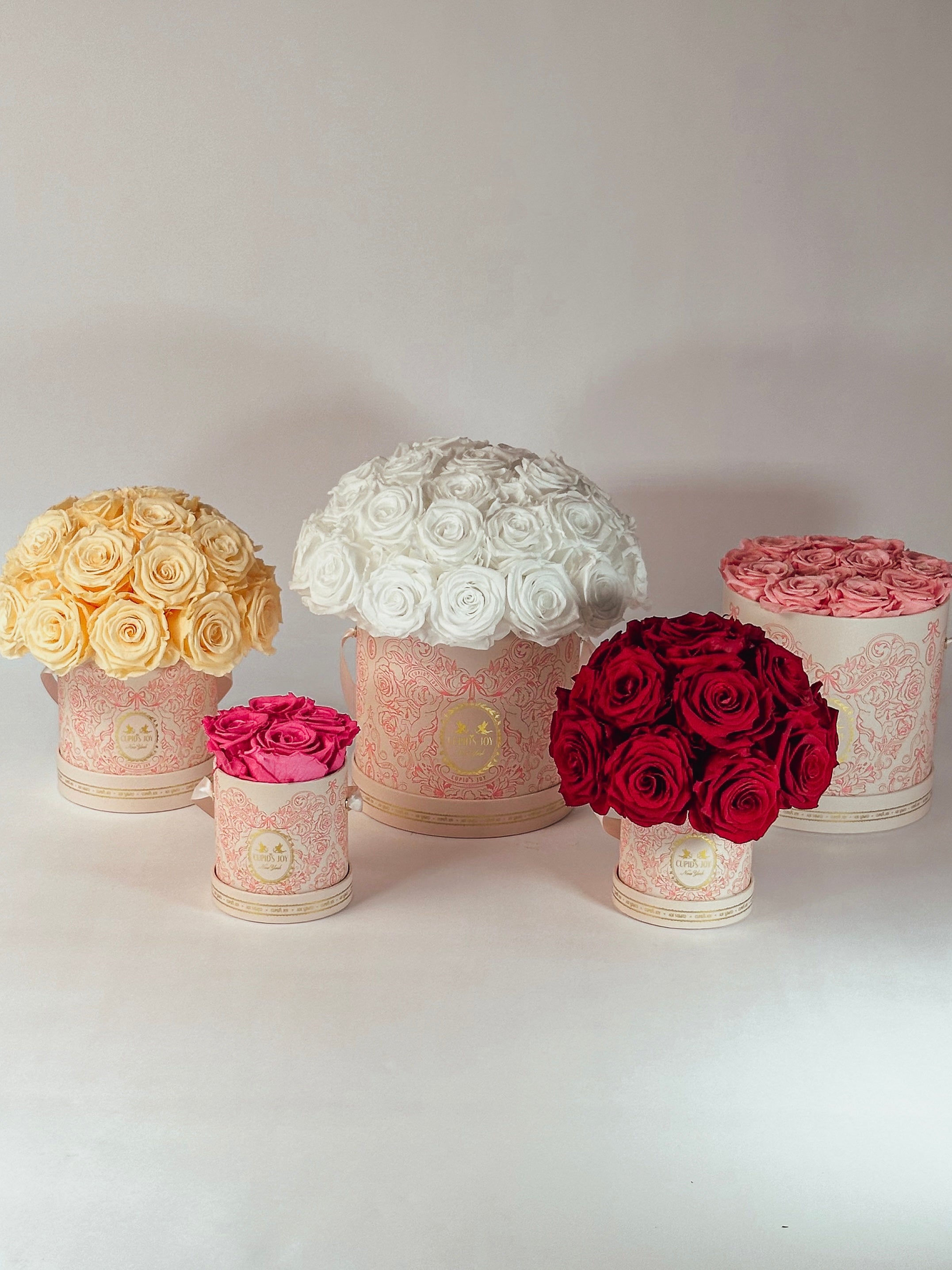 Set of decorative flower hat boxes with yellow, white, pink, and red flowers on a light background