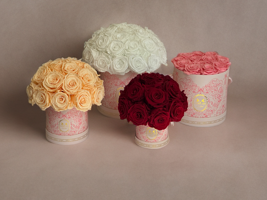 Four floral arrangements in cupid motif boxes on a neutral background